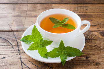 Cup of hot tea with mint and brown sugar on a wooden table