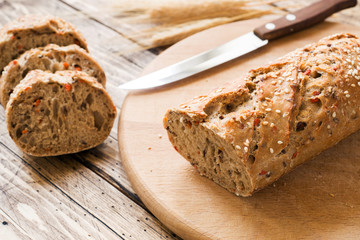 Fresh bread with sunflower seeds, sesame seeds and flax are cut into pieces on a cutting board.