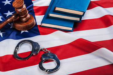 Gavel, handcuffs and american flag on wooden background.