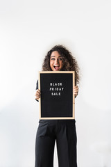 Happy beautiful woman with curly hair dressed on black with black felt board with letters on Black Friday Sale day