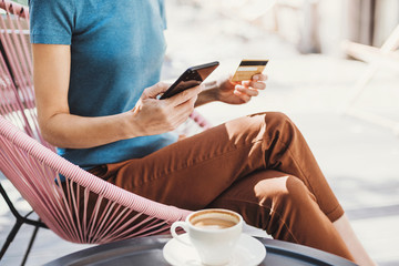 Young woman holding credit card and using smartphone, travel, vacations and online shopping concept
