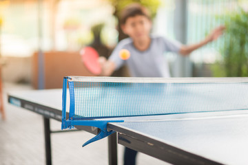 Kid playing table tennis outdoor with family