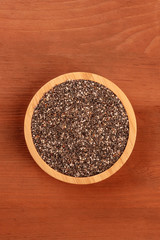 An overhead photo of chia seeds, shot from the top on a dark rustic wooden background with a place for text