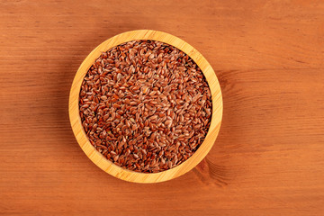 An overhead photo of flax seeds, shot from the top on a dark rustic wooden background with copy space