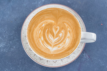 Сoffee cup on blue concrete table background. Latte or Cappuccino with frothy foam. Top view