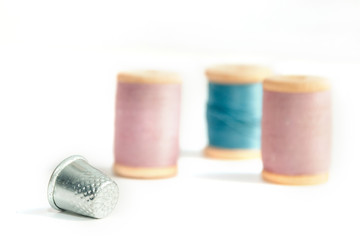 Close up thimble with spools of thread in soft focus isolated on white background
