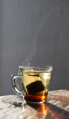 transparent mug with brewing tea in hot water in the morning light