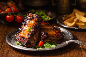 Roasted ribs, served on an old plate. Dark or balck background.