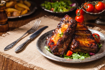 Roasted ribs, served on an old plate. Dark or balck background.