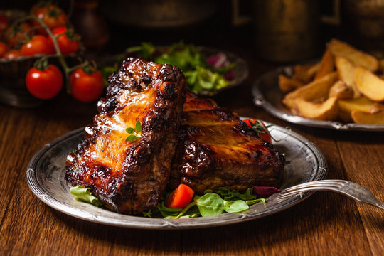 Roasted ribs, served on an old plate. Dark or balck background.