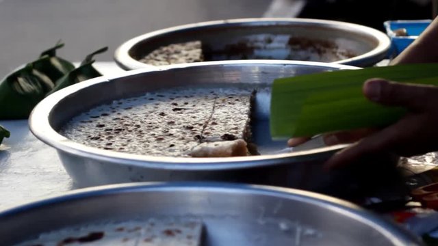 sweet Mae Hong Son local delicacy made from coconut milk and brown sugar being sold and served at a market in Northern Thailand