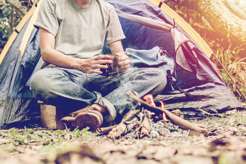 Asian young man sitting in the fire outside the tent, lonely camp in the forest.