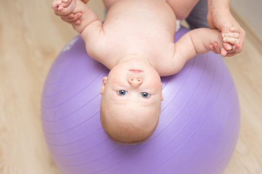 Mother And Her Baby Doing Exercises On A Ball