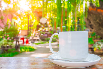 coffee cup on wooden table green outdoor nature garden background.
