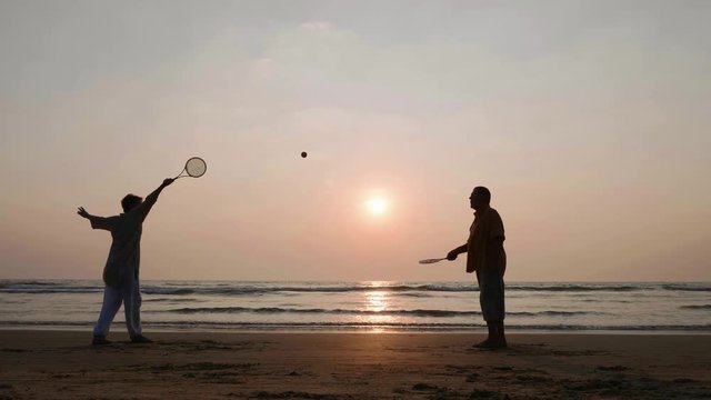 Active senior couple playing tai chi ballon ball at the beach.