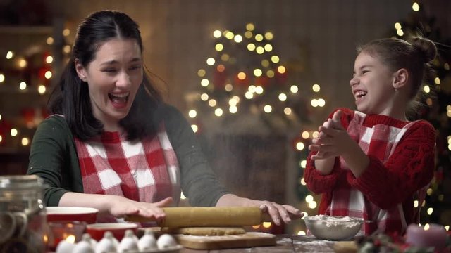 Merry Christmas and Happy Holidays. Family preparation holiday food. Mother and daughter cooking cookies.