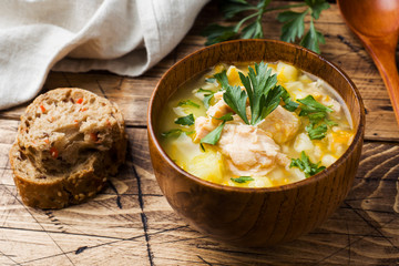 Fish soup in a wooden bowl with fresh herbs.