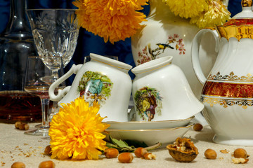 Dishes and flowers after party. Yellow flowers, turned cups of tea, empty glasses and bottles.