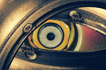 Unusual robotic eye in steampunk style in faded tones. Focused robot look. Golden background pattern close-up.