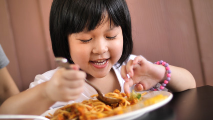 Happy Asian child eating delicious spaghetti