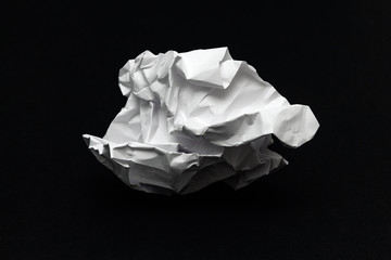 crumpled square lump of white paper on a black background