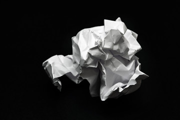 crumpled square lump of white paper on a black background