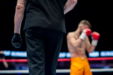 referee in black clothes in ring two fighters MMA, boxing martial arts competition