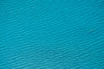 Fototapeta na wymiar Amazing textured background of calm azure clean water surface. Sunshine in mountain lake close up. Beautiful ripples on shiny water in sunny day. Wonderful relax texture.