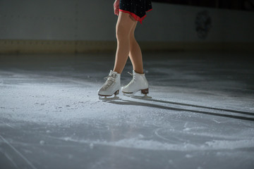 A cameraman is recording an ice skater when he performs in the ice rink. - obrazy, fototapety, plakaty