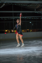 A young ice skater is looking very elegant and pleasant on the ice rink.