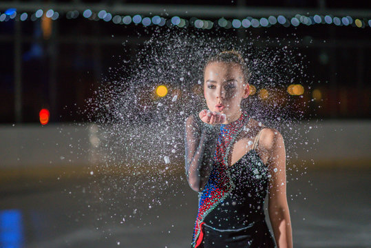 A Young Ice Skater Blows Ice From Her Hand.