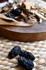 Chinese traditional medicine script. Herbal tea with jujubes, goji berries, gingseng roots and others on parchment paper on neutral background. Side view.