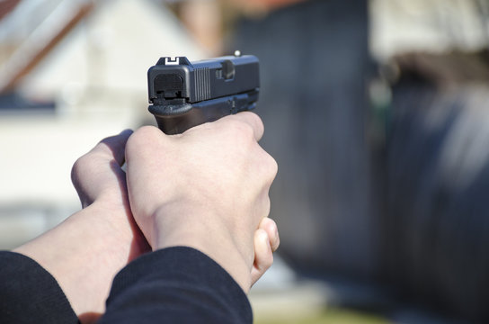 A gun in the hands of a man ready for a shot with blurred backfround