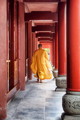 Buddhist monk walking along red wooden corridor of a temple