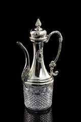 Closeup image of antique georgian silver metal jug isolated at black background.