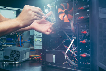 Technician repairing a computer, the process of replacing components on the motherboard. The technician hold the screwdriver for repairing PC. The concept of computer hardware, upgrade and technology