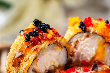 Macro image of hot tempura rolls decorated with teriyaki sauce and masago as a food background.