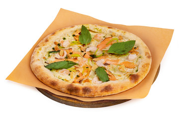 Tasty italian pizza with salmon, seafood and basil on a paper at wooden board isolated at white background.