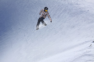 Snowboarder flying on the background of snowy slope. Extreme winter sports, snowboarding. Copy space.