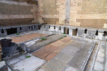 Ostia antica in Rome, Italy. Roman public latrine found in the excavations of Ostia Antica; unlike modern installations, the Romans saw no need to provide privacy for individual users.
