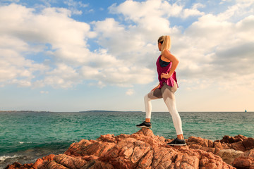Attractive sporty blonde woman looking at the horizon at the sea