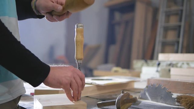 carpenter carves a chisel and mallet