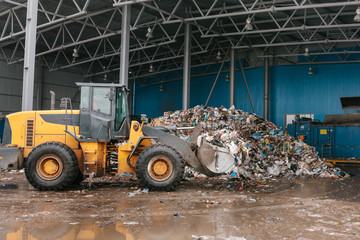 Special machinery or bulldozer work on the site of waste unloading at the plant for waste disposal. Technological process. Business for sorting and recycling.