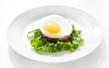 Meat cutlet with egg in a plate on a white background