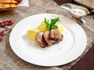 Dish of meat with potatoes on a plate on a wooden table