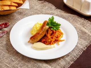 Fried sausage with vegetables on a plate on a wooden table