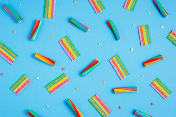 pattern wuth rainbow candies on a blue background, top view flat lay