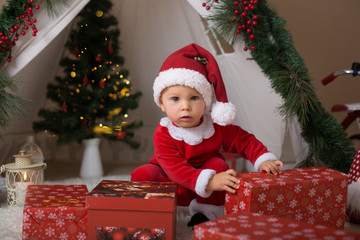 Fototapeta na wymiar Adorable little toddler baby boy dressed in canta claus costume, playing at home in front of crhistmas teepee