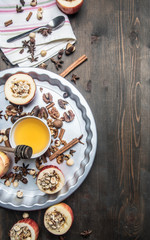 ingredients for cooking apples with honey and nuts, cinnamon and seasonings, sliced apples with filling on a rustic wooden background space for text