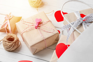 gift boxes, paper cut heart and shopping bag on a white wooden background. Valentine's Day decorations